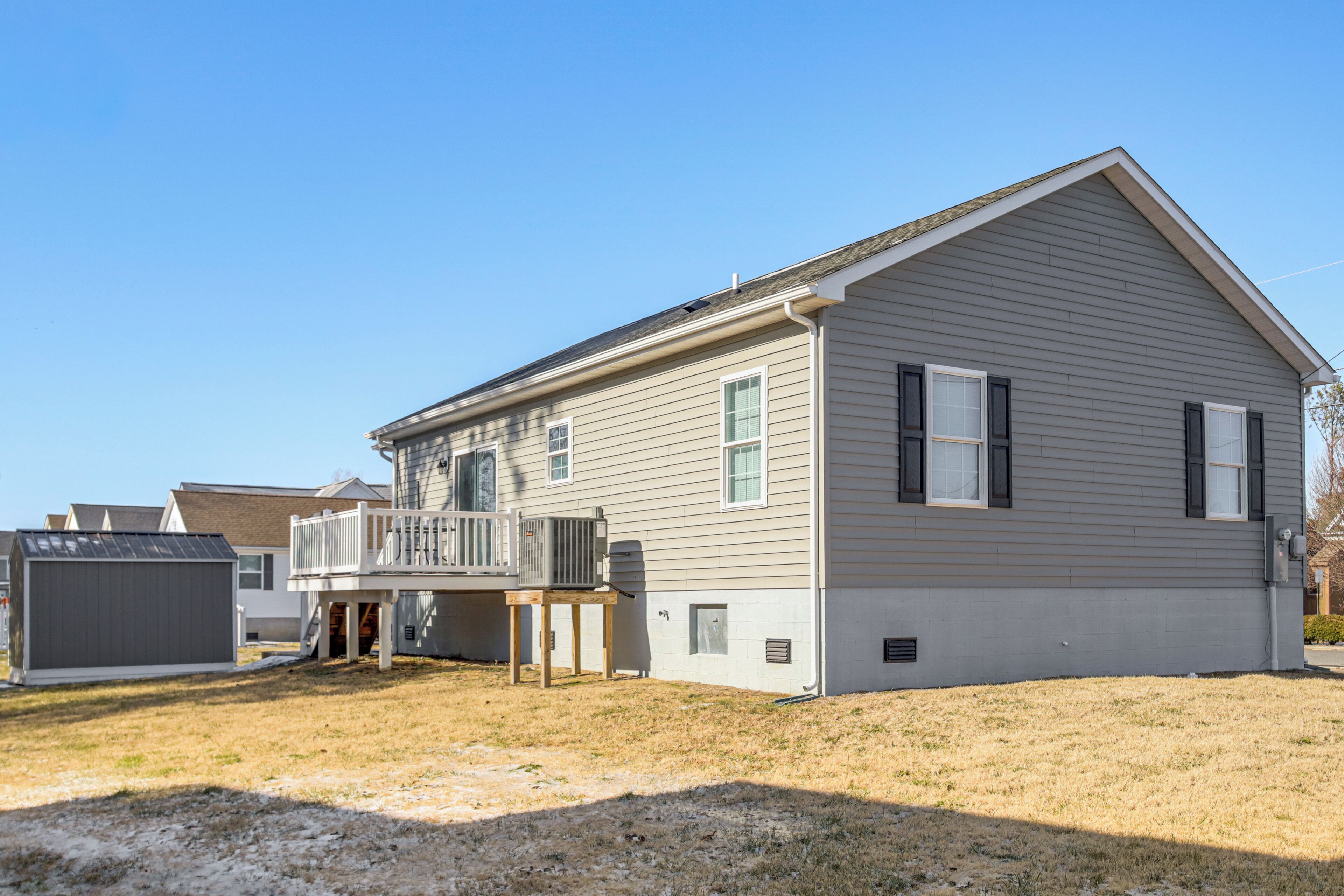 A single-story house with a front deck, a small attached garage, and a clear sky.