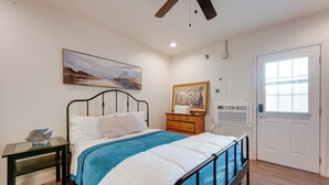 Una camera da letto con un letto, un comodino, una cassettiera, una ventola a soffitto, un quadro e una finestra.