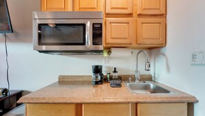 Una cucina con mobili in legno, un forno a microonde in acciaio inossidabile, una macchina da caffè e un lavello.