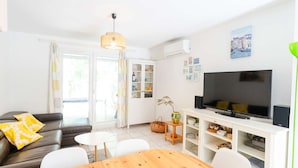 Uma sala de estar moderna com um sofá, uma mesa de jantar, uma TV e um armário branco.