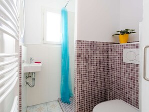 Une petite salle de bain avec une douche, un lavabo et des toilettes.