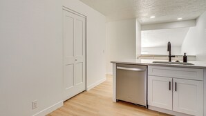 Una cocina moderna con armarios blancos, lavavajillas de acero inoxidable y un lavamanos empotrado.