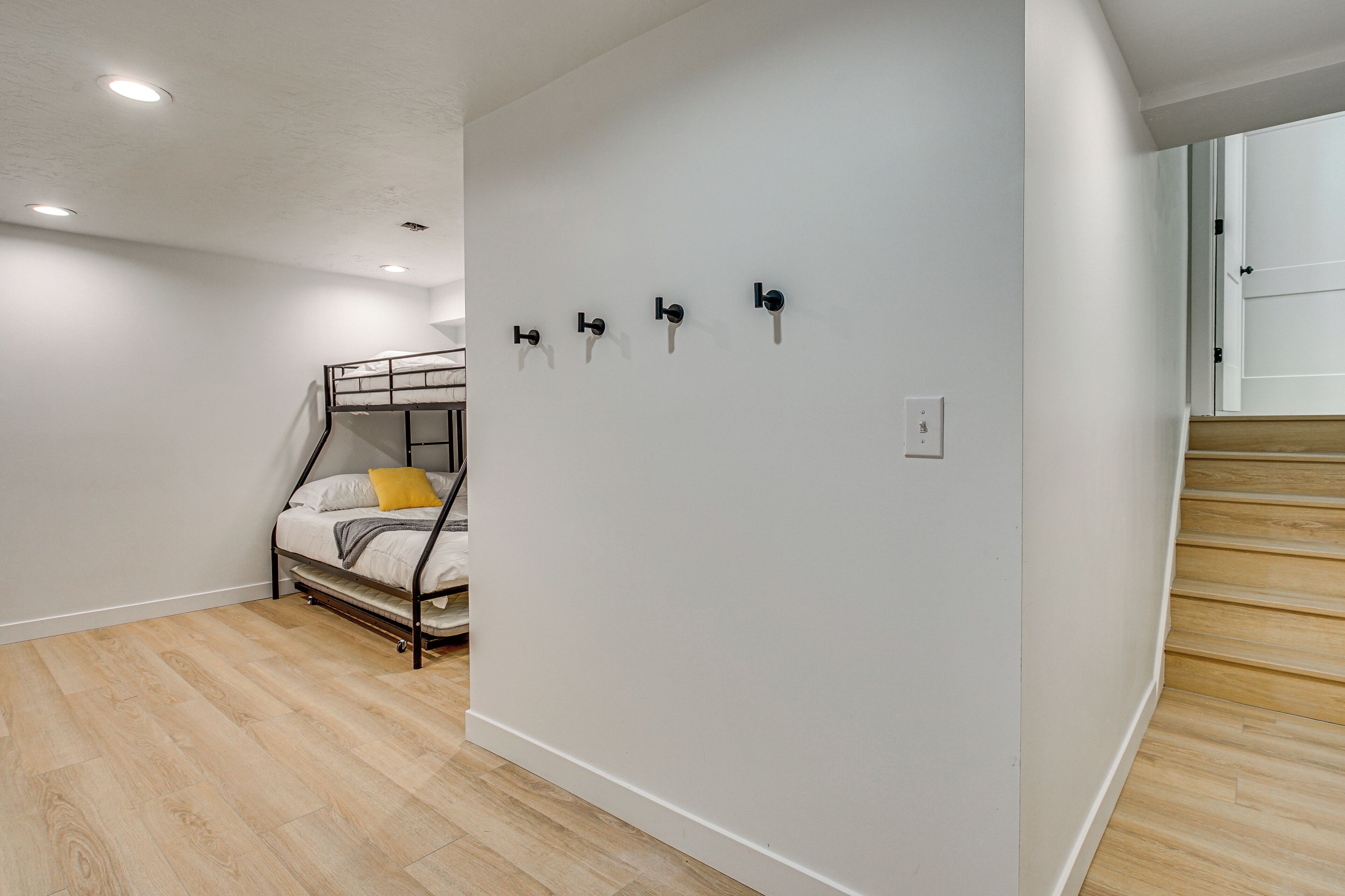A room with a bunk bed, white walls, and a wooden staircase.
