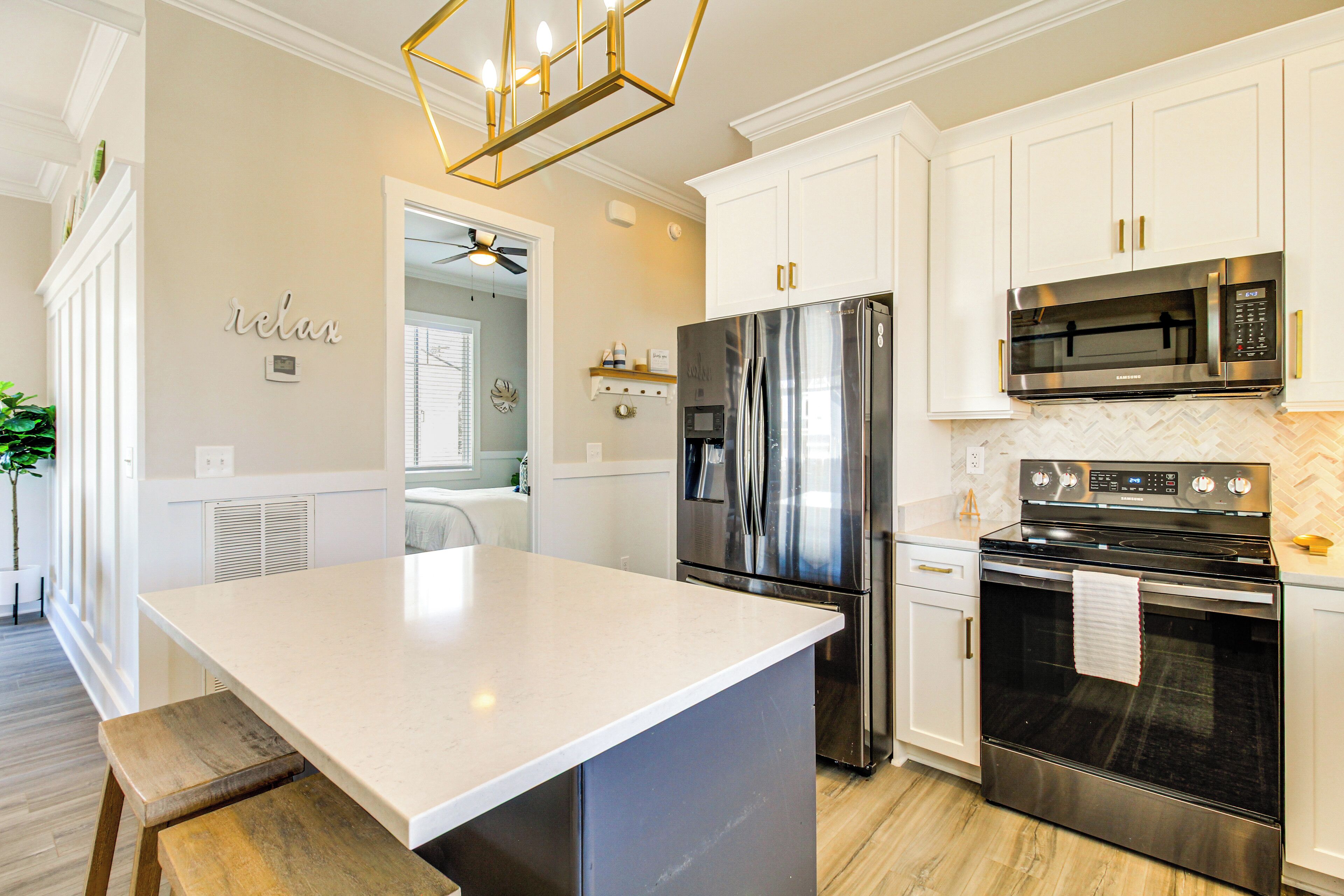 A modern kitchen with a central island, stainless steel appliances, and white cabinetry.