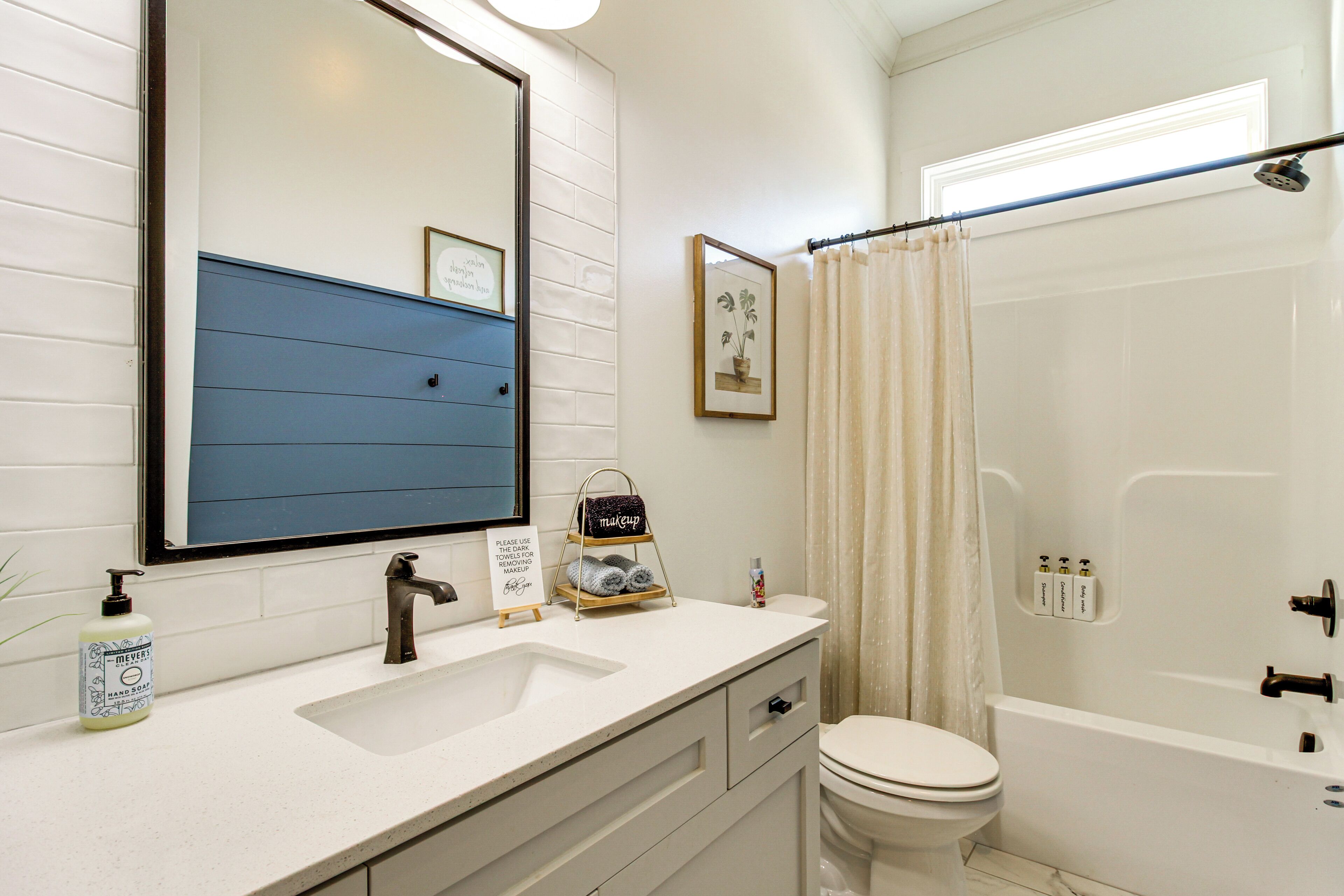 A bathroom with a white sink, a mirror, a toilet, and a bathtub.
