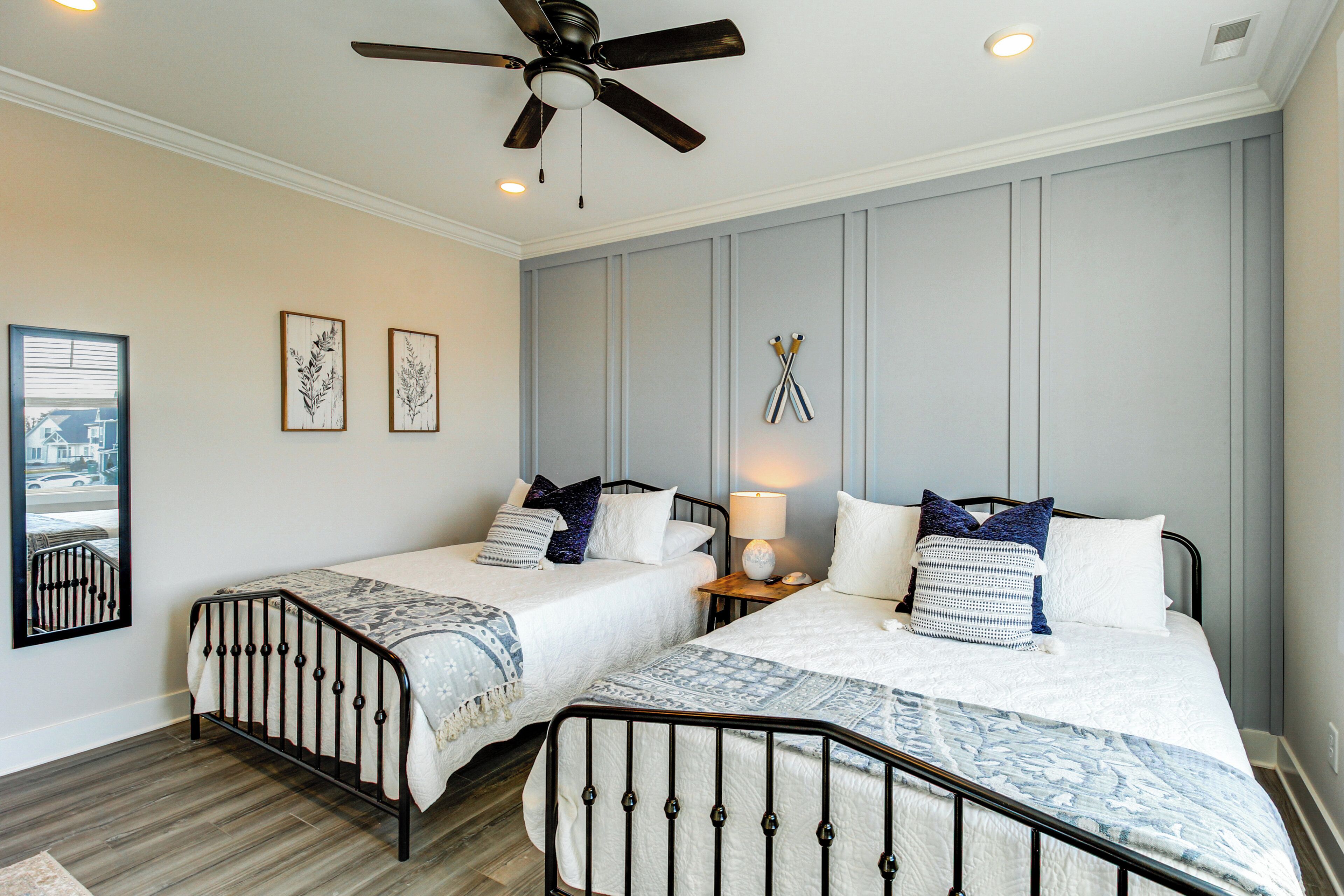 A bedroom with two beds, a ceiling fan, and a nightstand with a lamp.