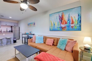A modern living room with a brown sofa, a coffee table, and a painting of sailboats on the wall.