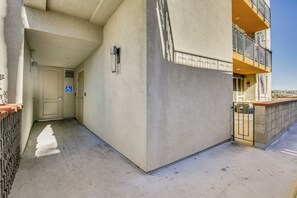 Een gevel van een gebouw met een rolstoeltoegankelijke ingang, een hekwerkbalcon en een heldere lucht.