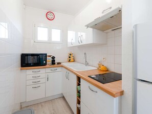 Een moderne keuken met witte kasten, een magnetron, een spoelbak en een fornuis.