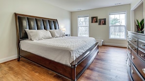 A bedroom with a large bed, wooden floor, a dresser, and two windows. - Walk to Dtwn & Campus! Spacious Hampton Home (Hampton)