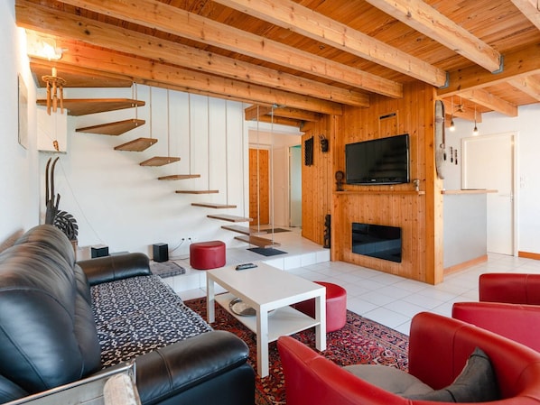 Uma sala de estar moderna com escada, TV de tela plana e lareira.