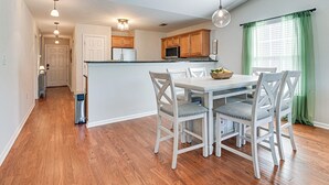 Una cocina moderna con armarios de madera, una isla central y un comedor con sillas blancas.