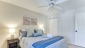 Un dormitorio con cama, mesitas de noche, ventilador de techo y una obra de arte en la pared.