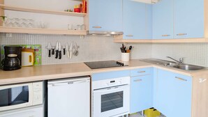 Keittiössä on vaaleansiniset kaapit, mikroaaltouuni, astianpesukone, liesi ja pesuallas.