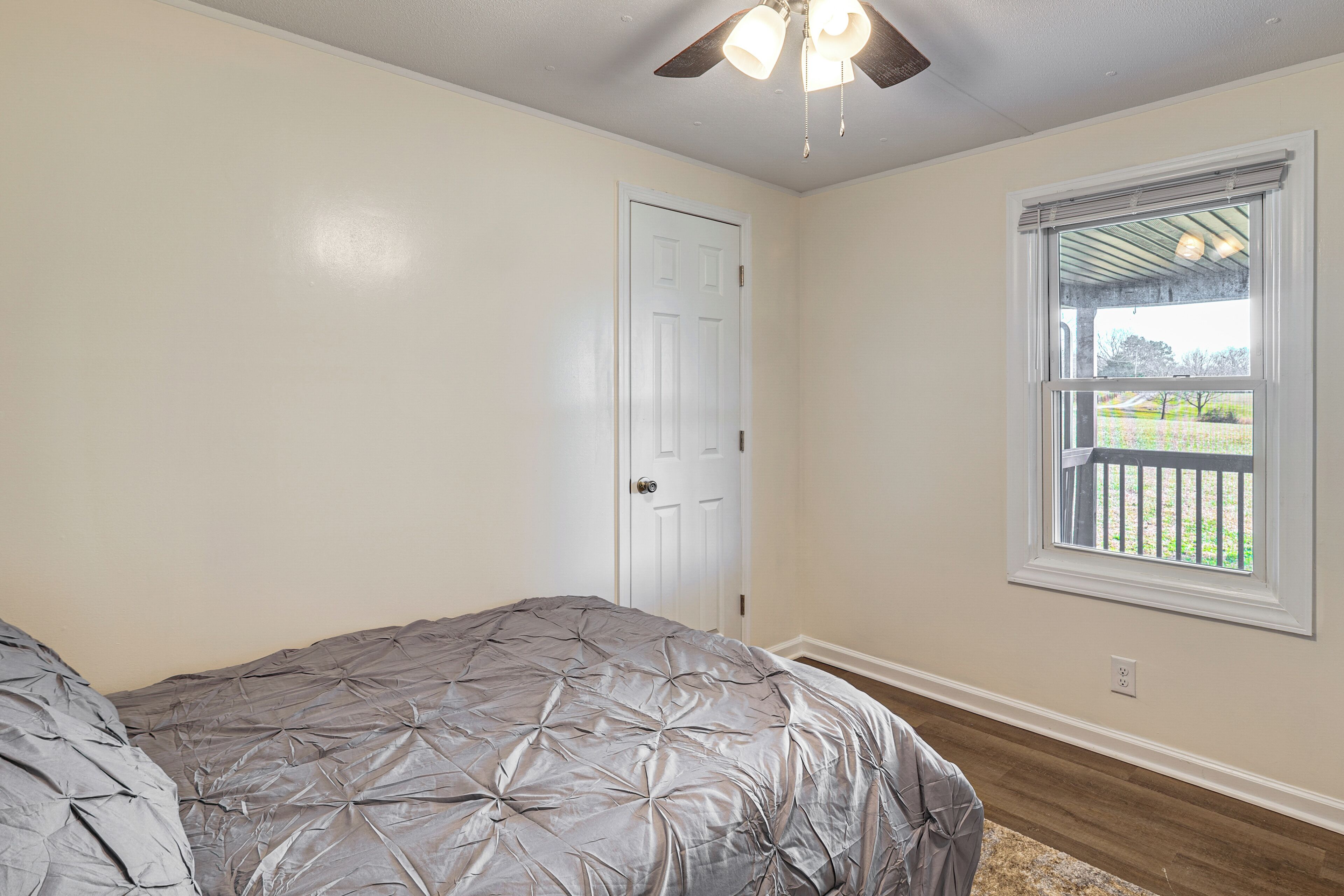Une chambre à coucher avec un lit, une porte, une fenêtre et un ventilateur de plafond.