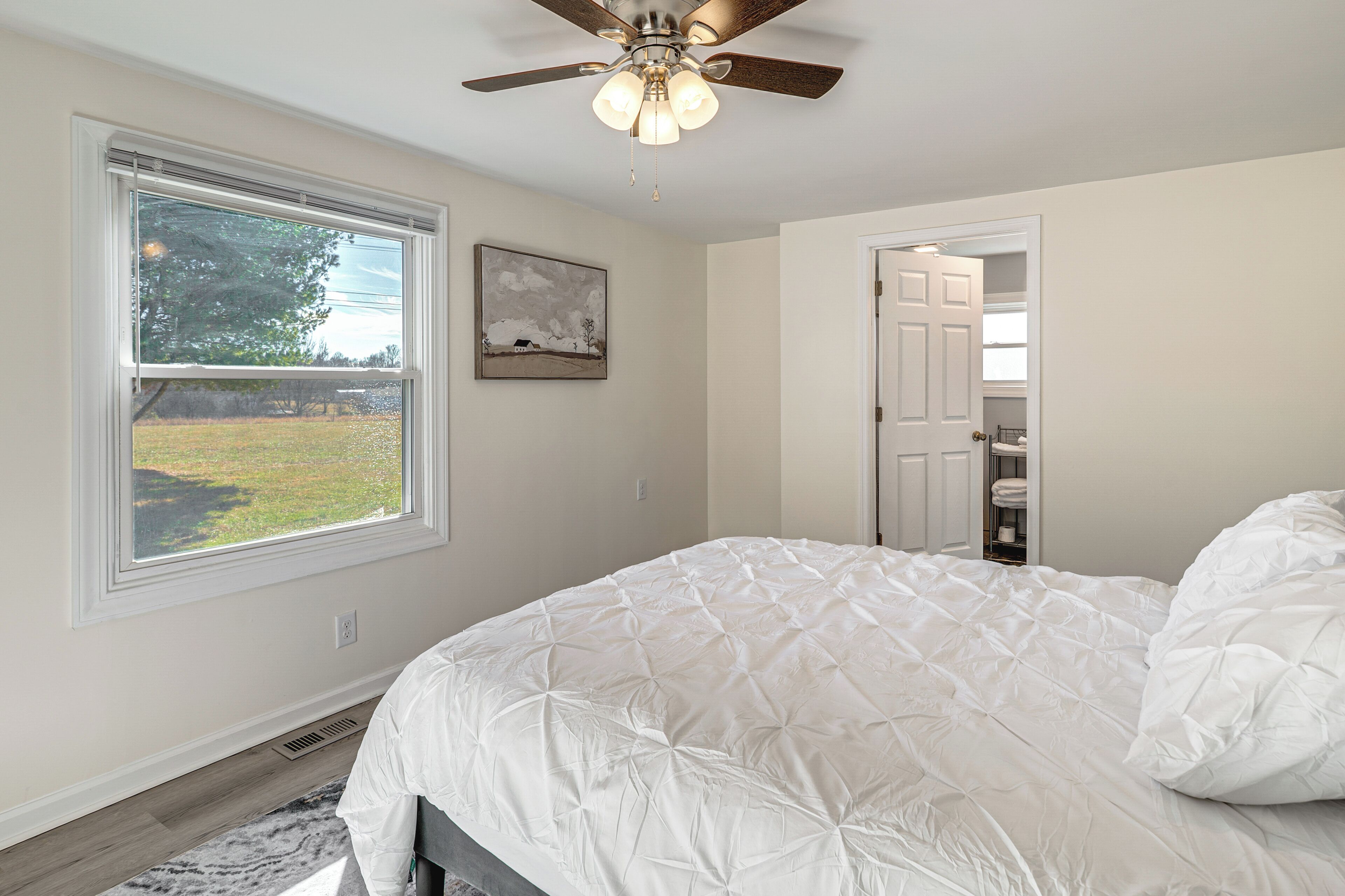 Quarto com uma cama grande, um ventilador de teto, janela com vista para o exterior e porta que dá para um armário.