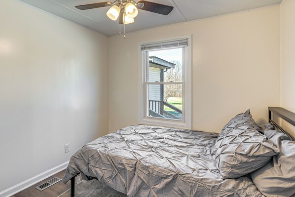A bedroom with a bed, a ceiling fan, a window, and a door. - Secluded Family Home in Springfield, Pets Welcome! (Springfield)