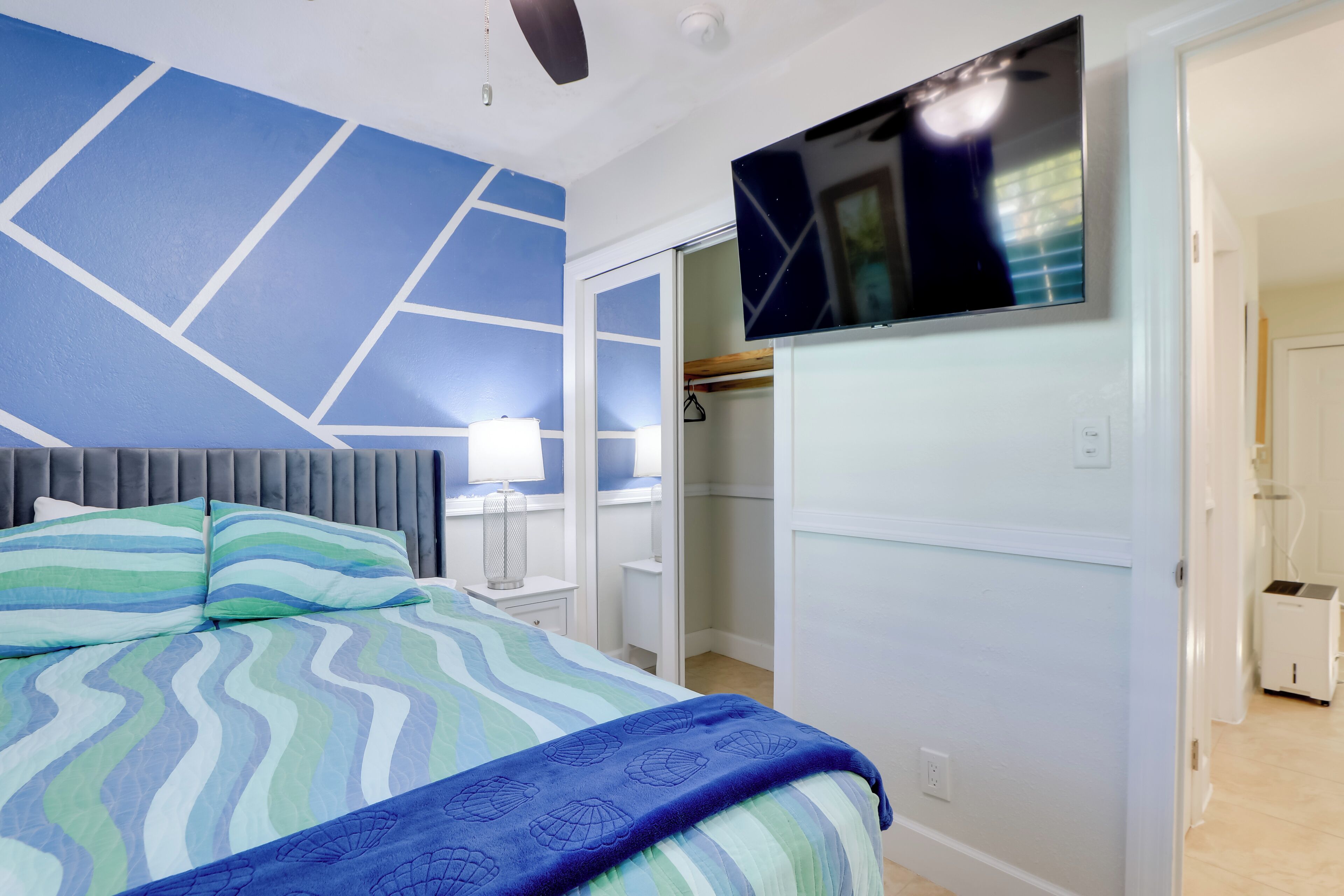 Une chambre à coucher avec un lit, un téléviseur fixé au mur et un placard.