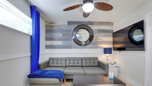 A modern living room with a sectional sofa, a coffee table, a ceiling fan, and a large wall clock. - Walk to Everything! Johns Pass Gem w/ Dock Access (Madeira Beach)