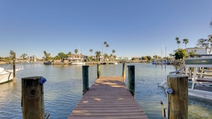 A wooden dock leading to a marina with boats and houses in the background. - Walk to Everything! Johns Pass Gem w/ Dock Access (Madeira Beach)