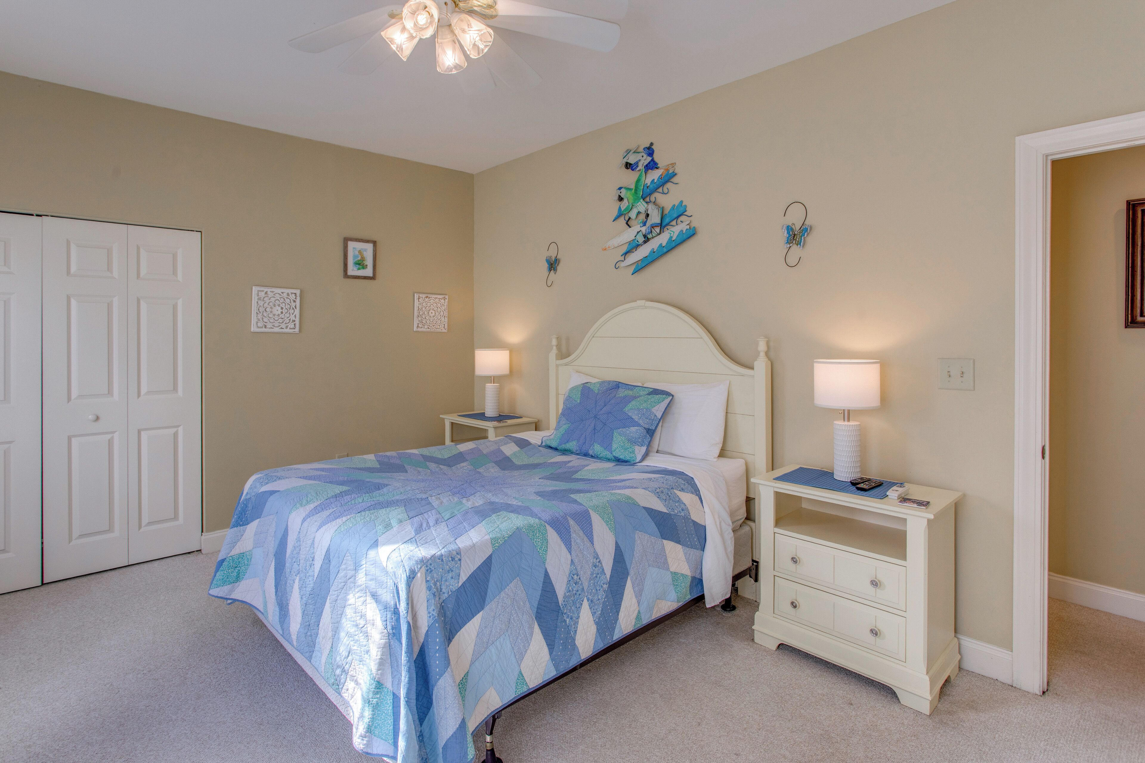 A bedroom with a bed, nightstands, a dresser, and a door.