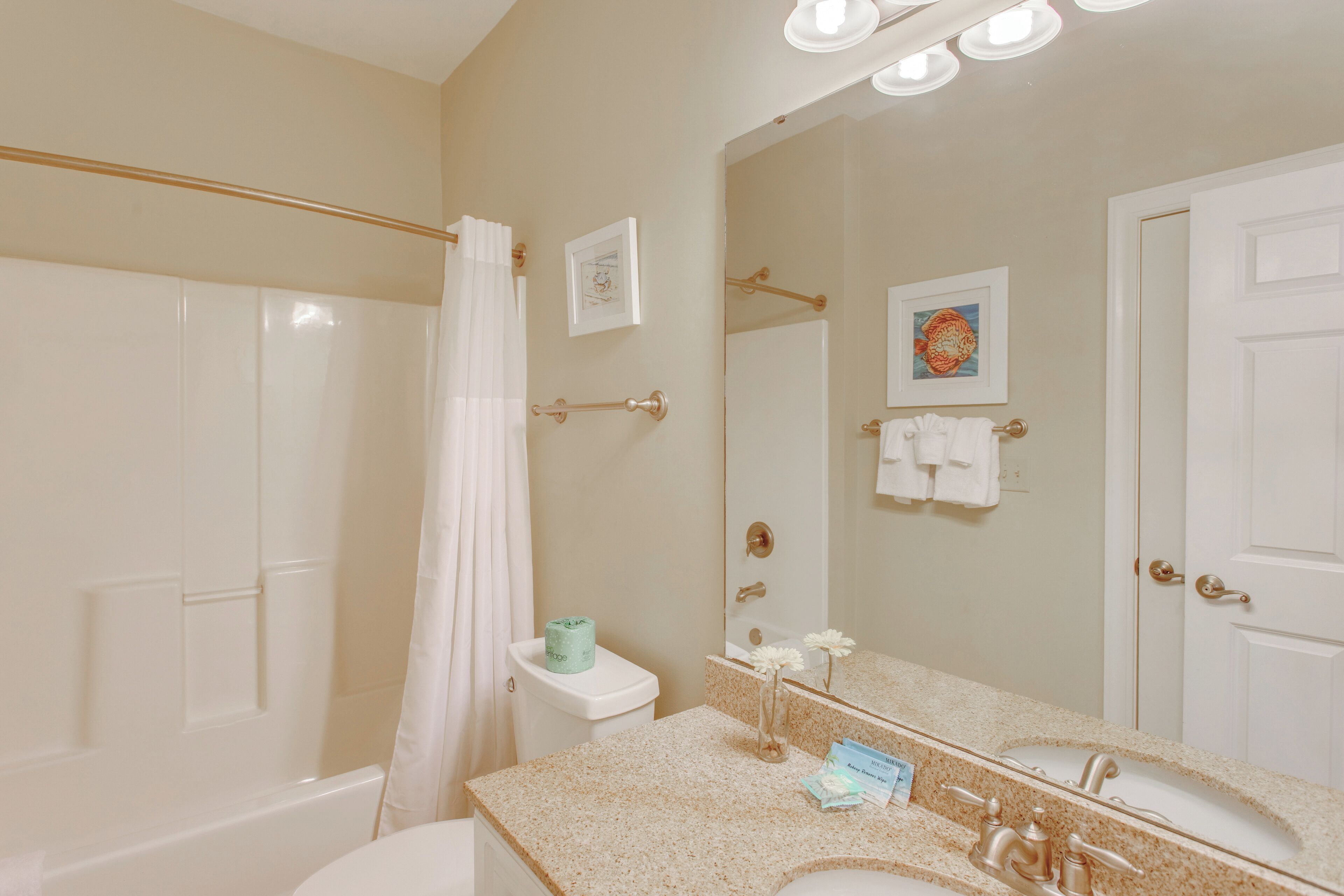 A bathroom with a bathtub, toilet, sink, and a large mirror.