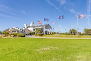 A large building with a covered porch and multiple flags. - Golf, Swim & Relax: Condo at World Tour Resort! (Myrtle Beach)