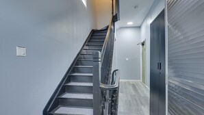 A staircase with a metal railing, a closed garage door, and a light switch on the wall. - Explore Nyc, Parks & Beaches! Top-floor Apt (Mount Vernon)