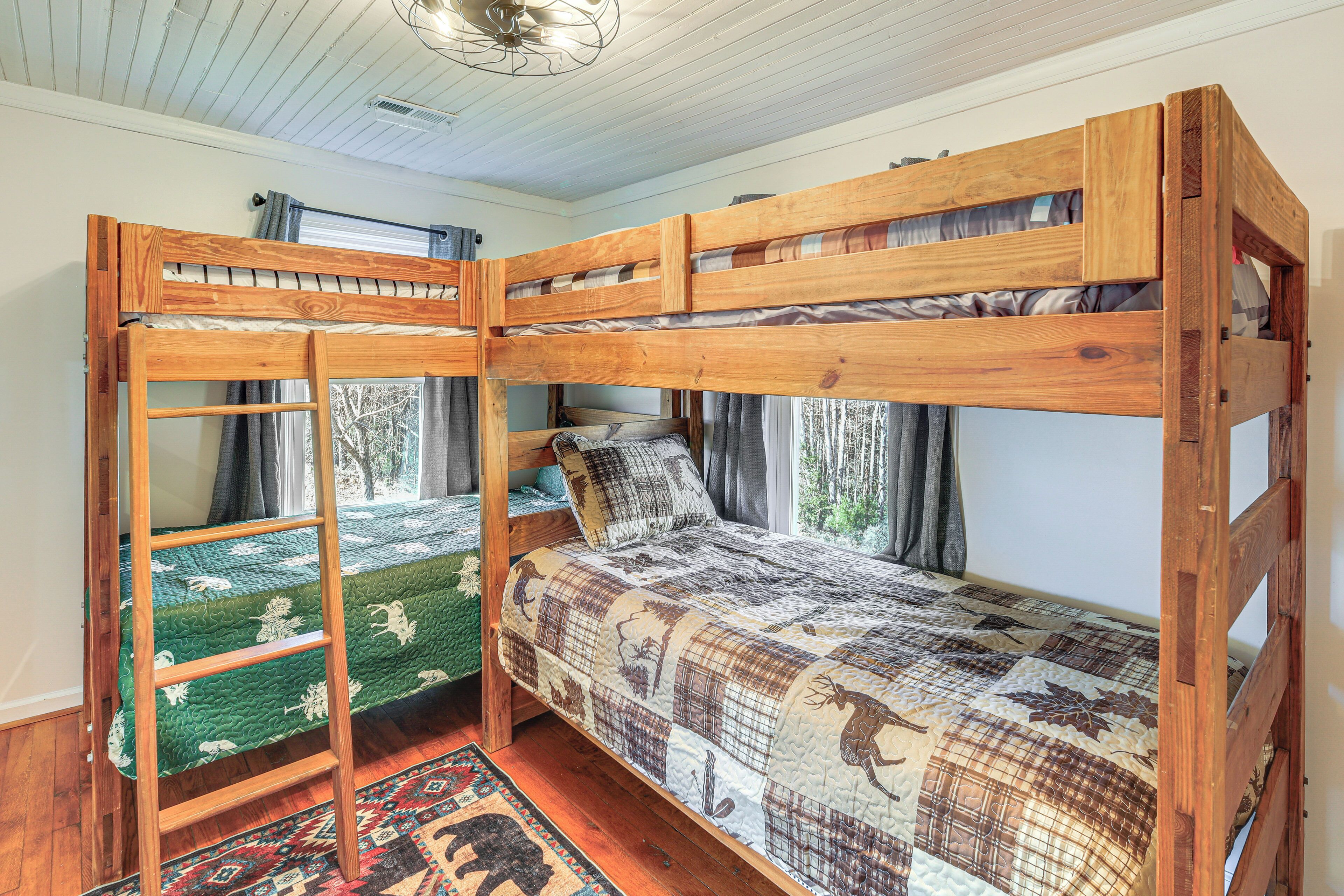 A bunk bed with a ladder, a window with curtains, and a patterned bedspread.