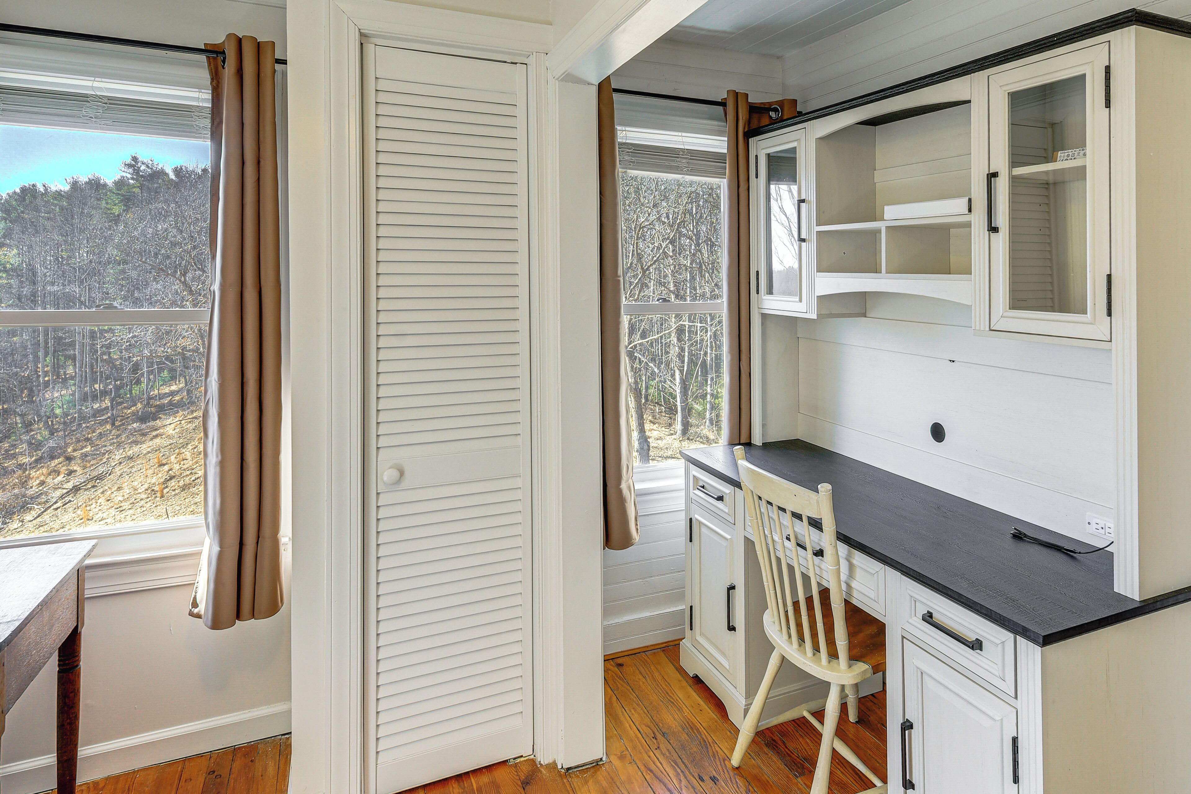 A room with a desk, chair, and a cabinet with open shelves.