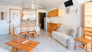 A compact living space with a dining area, sofa, and kitchenette. - Seaside Apartment in Gruissan with Parking & WiFi Option (Gruissan)
