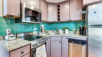 Una cocina con estufa de acero inoxidable, lavavajillas y refrigerador.