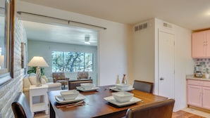 A dining area with a wooden table set for four, white plates, and a white lamp. - Hike, Golf & Dine: Tucson Retreat w/ Mtn Views! (Tucson)