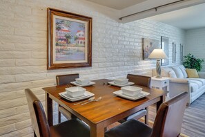 A dining area with a wooden table set for four, white plates, and a framed painting on the wall. - Hike, Golf & Dine: Tucson Retreat w/ Mtn Views! (Tucson)