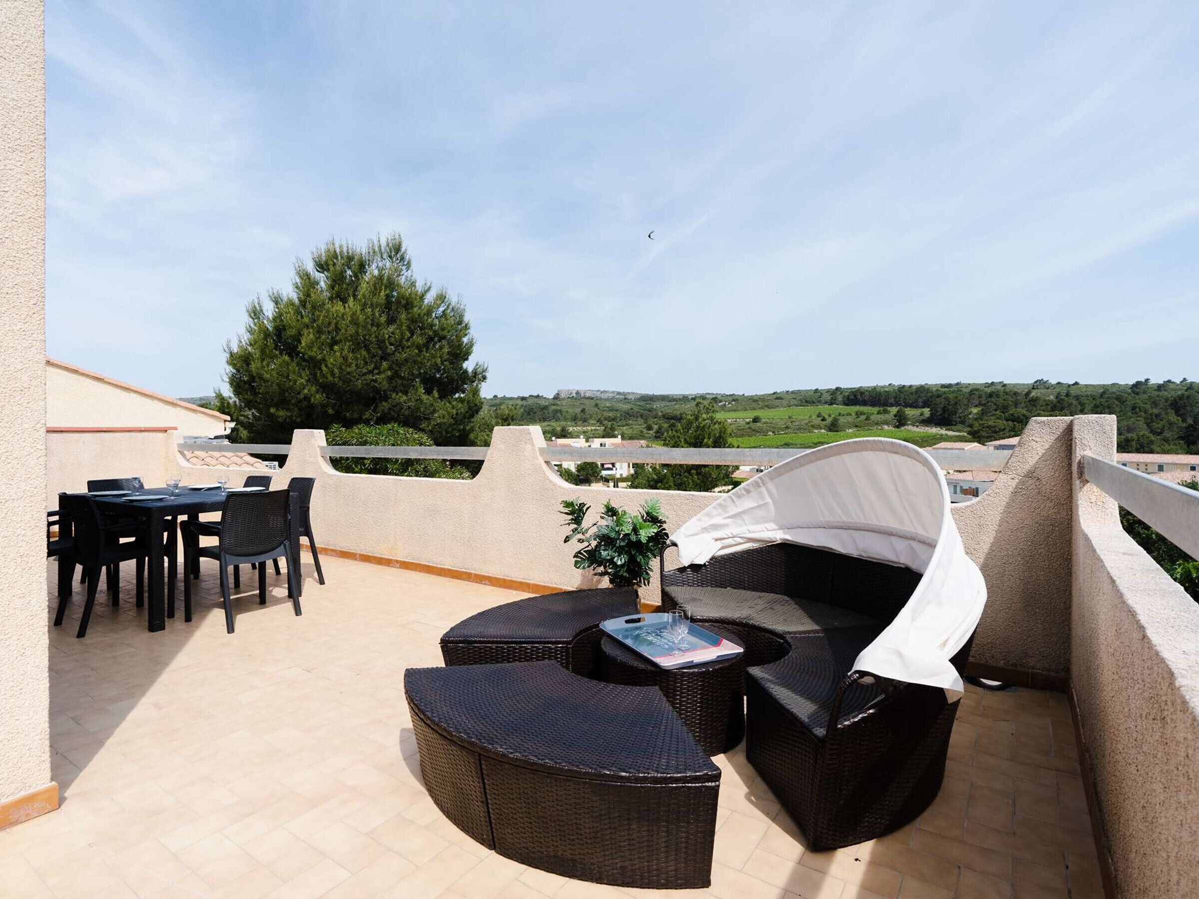 Een terras met rieten meubels, een tafel en stoelen.