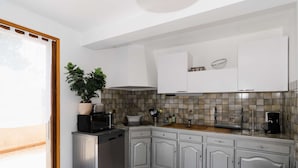 A modern kitchen with white cabinets, a stainless steel dishwasher, a microwave, and a sink. There is a potted plant on the counter and a basket of dishes. - Spacious family villa in Narbonne-Plage for 6 people, private parking, pets allowed (Narbonne-Narbonne Plage-Narbonne Plage)