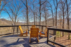 A wooden deck with rocking chairs and a railing, overlooking a forested area with mountains in the background. - Mtn-view Cabin w/ Hot Tub Near Blairsville Trails (Blairsville)