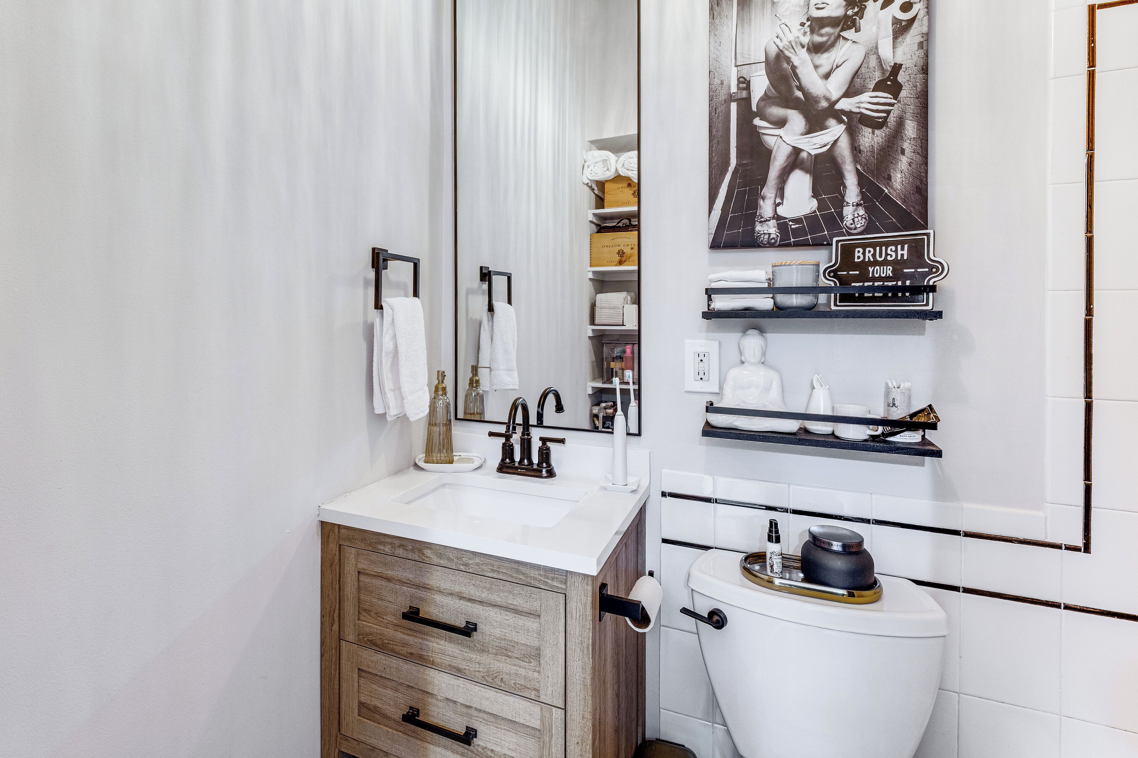 Un bagno moderno con un mobile bagno in legno, un lavandino bianco e un water con funzione bidet. Sopra il mobile bagno c'è uno specchio grande e un porta asciugamani sulla parete.