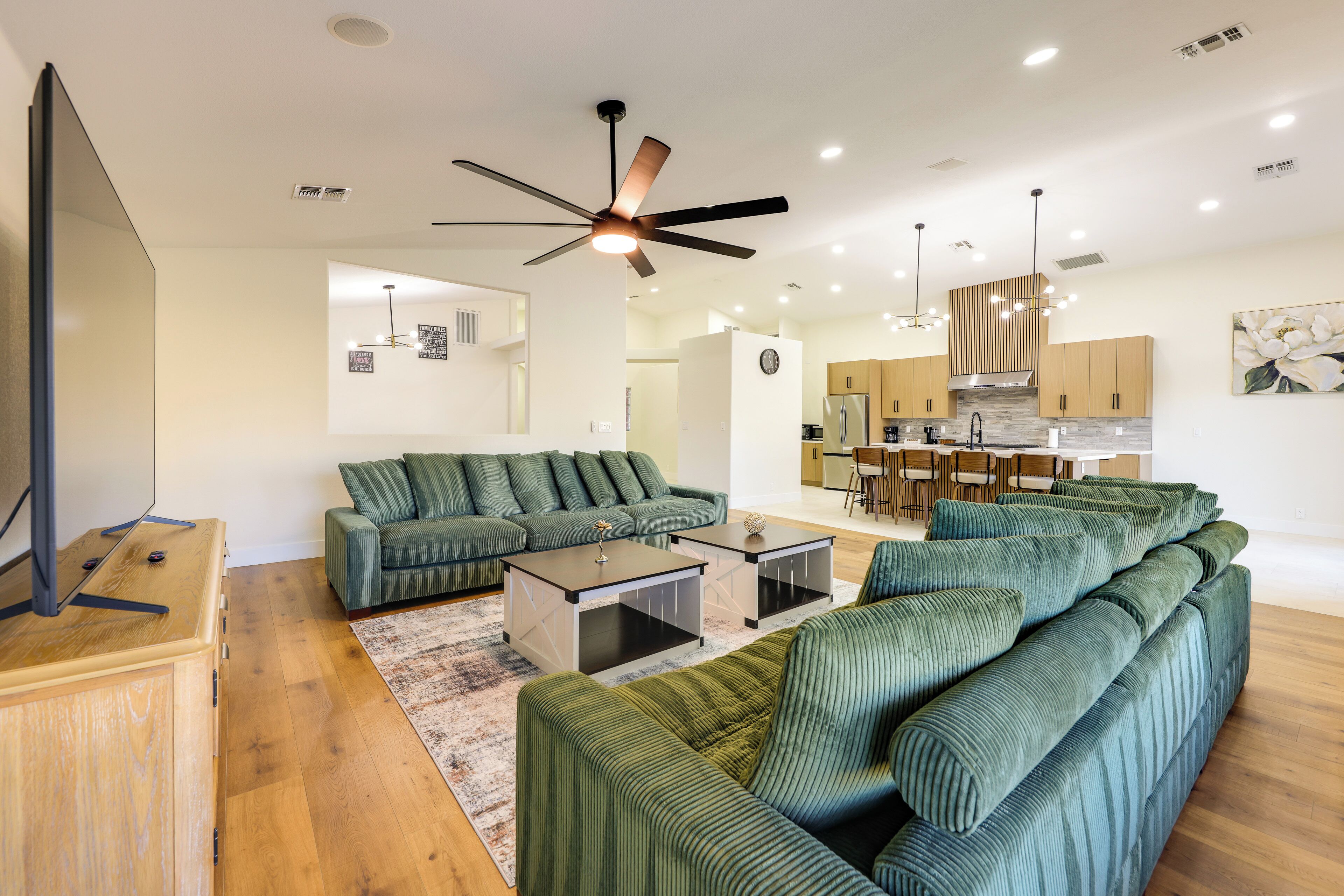 Una sala de estar moderna con un sofá verde, una mesa de centro y un televisor sobre un mueble de madera.
