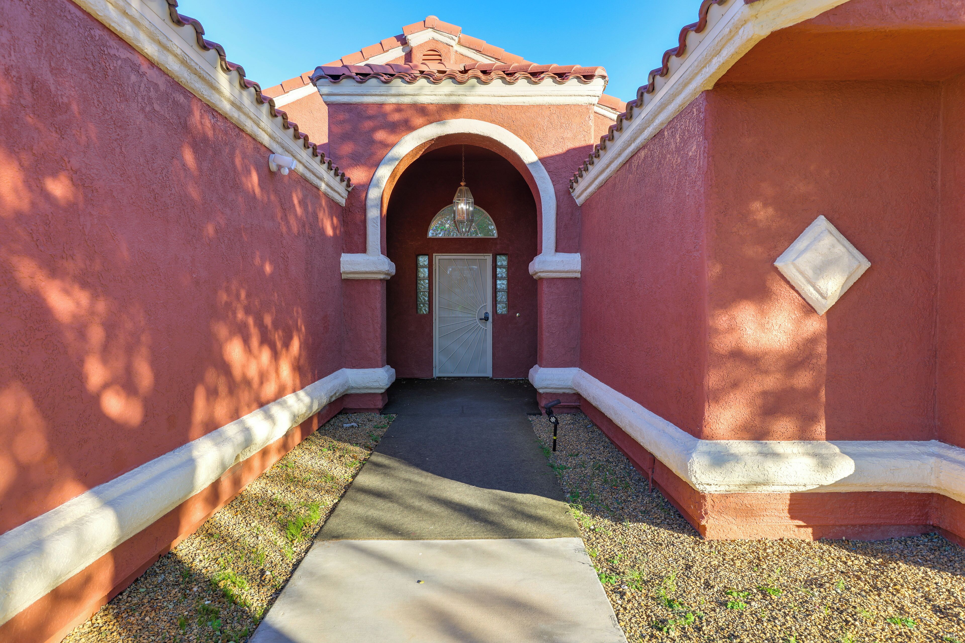 A narrow pathway leading to a building with a red facade and white trim.