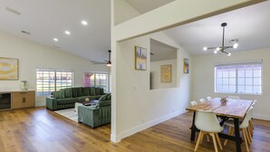 A spacious living area with a wooden floor, a green sofa set, a dining table with chairs, and a ceiling fan. - Patio w/ Fairway View! Pet-friendly Mohave Home (Fort Mohave)