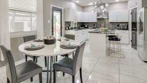 A modern kitchen with white cabinets, a marble countertop, and a dining area with a round table and chairs. - 3 Mi to Randolph Afb: San Antonio Area Home (Universal City)