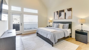 A bedroom with a bed, bedside tables, a desk, and a large window with blinds. - 4 Mi to NRG Stadium: Modern Group Retreat (Houston)