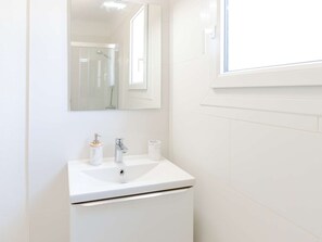 A white bathroom with a sink, a mirror, and a window. - Renovated house near the sea with air conditioning and WIFI (Fleury-Saint-Pierre-la-Mer)