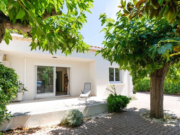 A modern house with a patio, a sliding glass door, and a chair outside. - Renovated house near the sea with air conditioning and WIFI (Fleury-Saint-Pierre-la-Mer)
