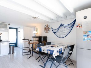 A dining area with a table set for four, a kitchen area with a sink and stove, and a hammock on the wall. - Cozy pavilion with terrace 250m from the beach! (Narbonne)