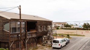 Un edificio de madera con balcón y un coche estacionado adelante.