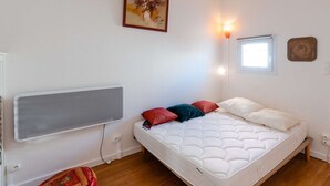 Quarto com cama, radiador, luminária na parede, janela e pintura.