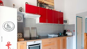 Cozinha compacta com geladeira, forno, micro-ondas e armários vermelhos.