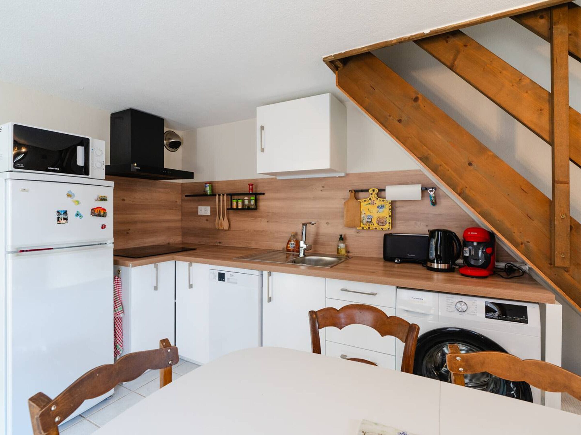 Una cocina compacta con microondas, refrigerador, lavaplatos y lavadora.